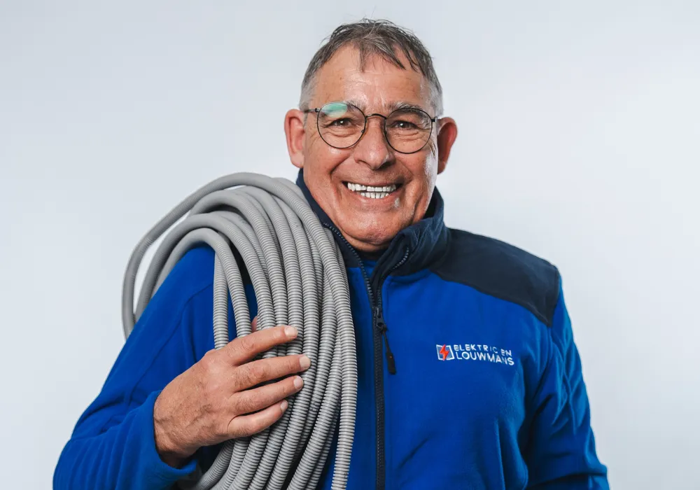 Elektricien van Louwmans met een rol installatiekabel over de schouder