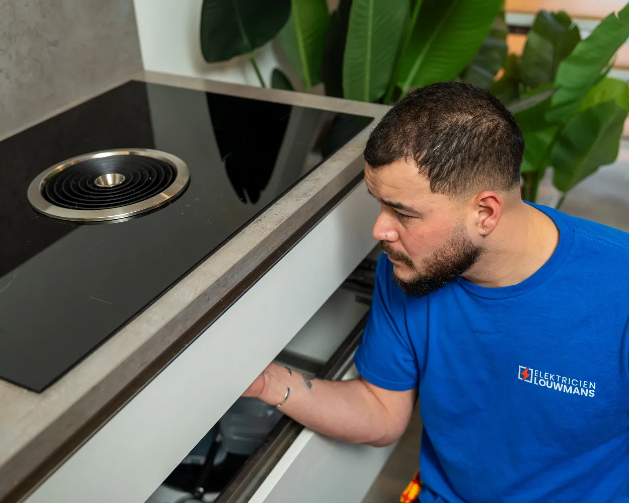 Elektricien van Louwmans sluit onder het aanrecht een inductiekookplaat aan